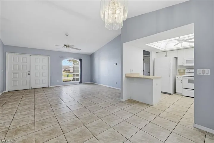 Kitchen featuring a ceiling fan, white appliances, white cabinets, light tile patterned floors, and lofted ceiling