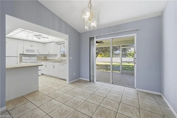 Kitchen featuring lofted ceiling, white cabinetry, light countertops, white appliances, and a ceiling fan