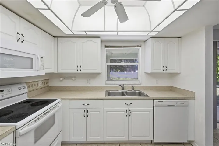 Kitchen featuring white appliances, light countertops, white cabinets, and ceiling fan