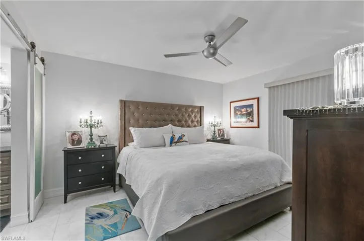 Sleek ceiling fan with integrated lighting, a tufted headboard, and tile flooring