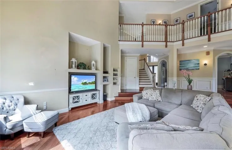 Living room featuring hardwood / wood-style floors, a high ceiling, and ornamental molding