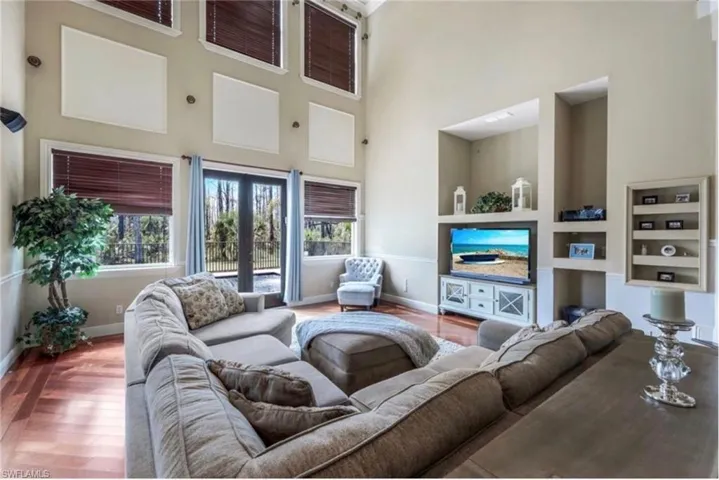 Living room with a high ceiling, built in shelves, and hardwood / wood-style floors