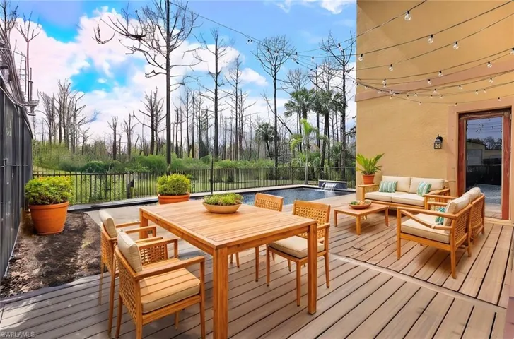 Wooden terrace with a fenced in pool and an outdoor living space