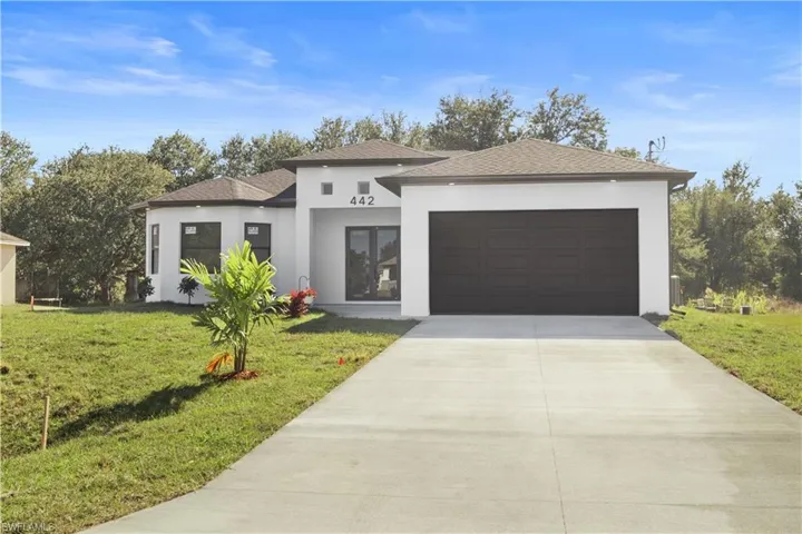 View of front of house featuring stucco siding, driveway, a front lawn, and roof with shingles