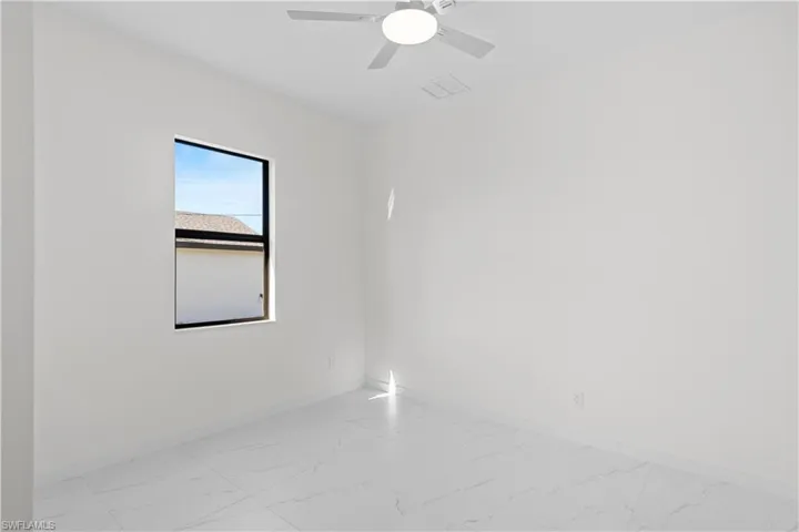 Empty room featuring light marble finish floors and ceiling fan