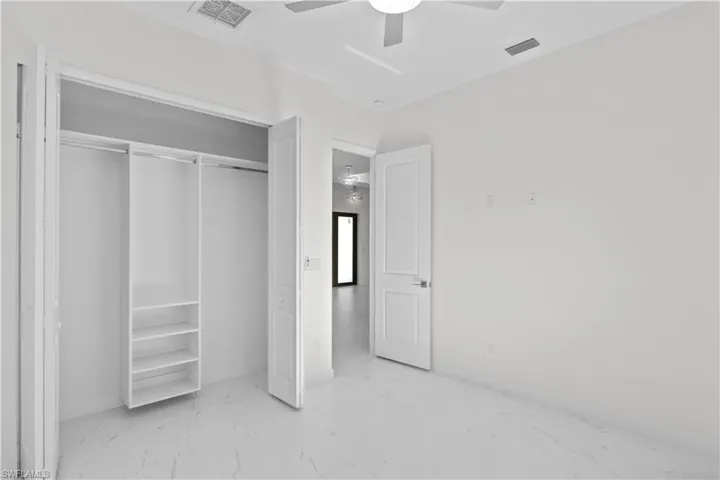 Unfurnished bedroom with light marble finish floors, a ceiling fan, and a closet