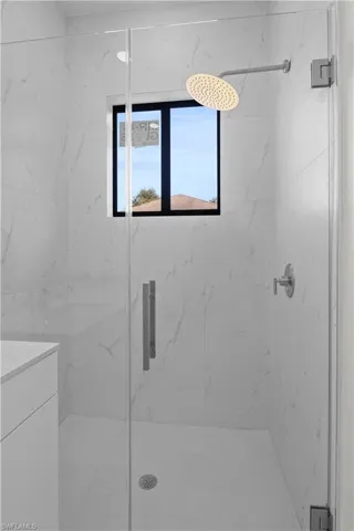 Full bath featuring a marble finish shower and vanity
