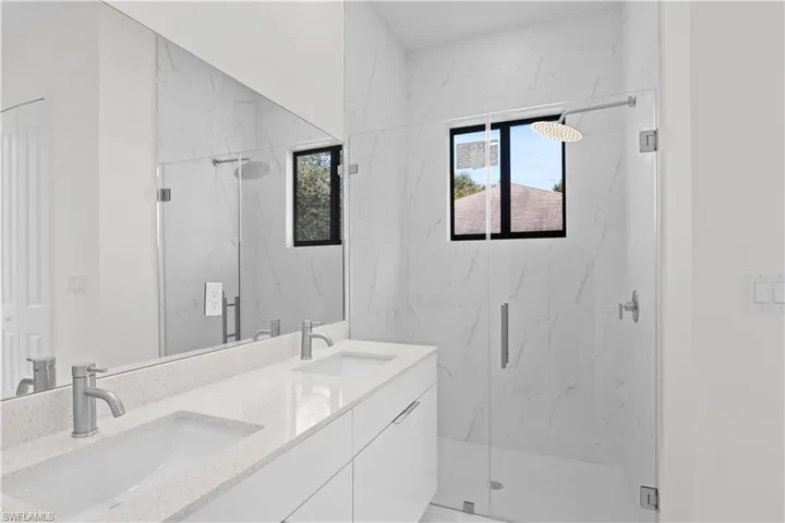 Bathroom with double vanity and a marble finish shower