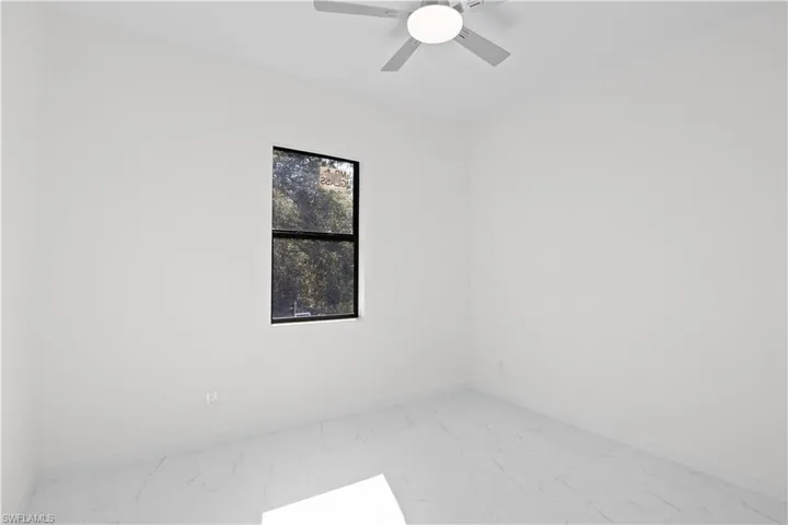 Empty room featuring light marble finish floors and ceiling fan