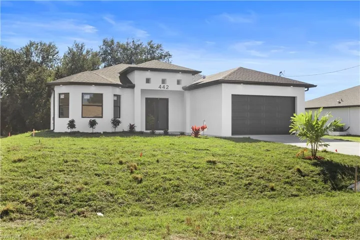 Prairie-style home featuring stucco siding, driveway, a front lawn, roof with shingles, and an attached garage