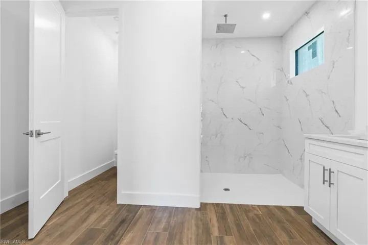 Spacious shower enclosure with marble-look wall tiling and a rainfall showerhead