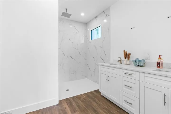 Modern bathroom featuring a spacious walk-in shower with full-height marble-patterned tile, a square rain shower head, and a transom window