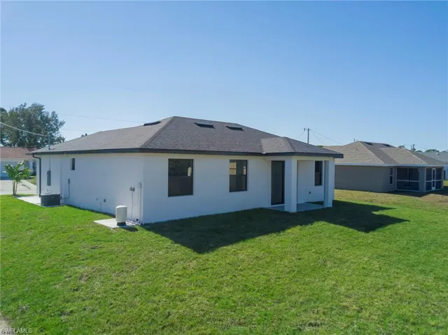 Rear view of property with a lawn, stucco siding, roof with shingles, and a patio area