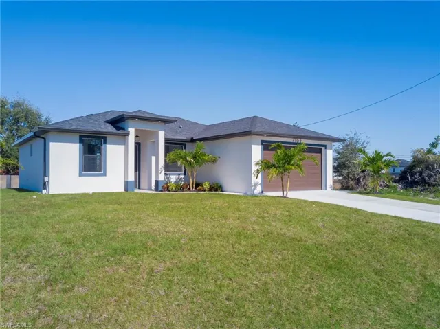 Prairie-style home with stucco siding, a front yard, driveway, and an attached garage