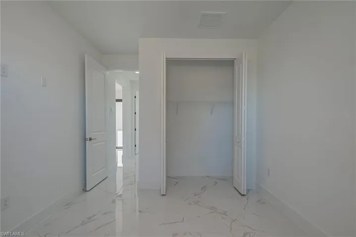 Unfurnished bedroom with light marble finish floors and a closet