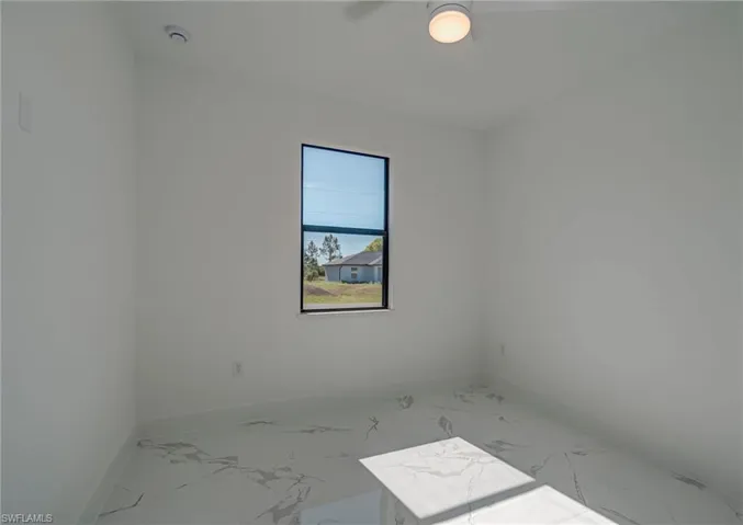 Empty room featuring marble look tile flooring and baseboards