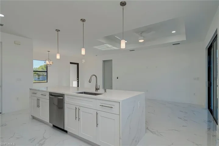 Kitchen featuring hanging light fixtures, white cabinetry, recessed lighting, and a tray ceiling