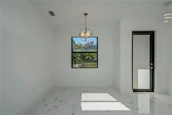 Unfurnished dining area featuring light marble finish floors and a chandelier