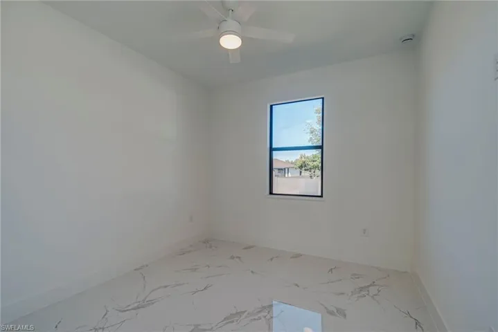 Empty room with light marble finish floors and a ceiling fan