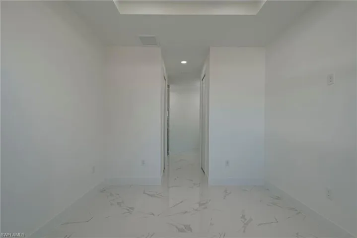 Spare room featuring recessed lighting, light marble finish floors, and a raised ceiling