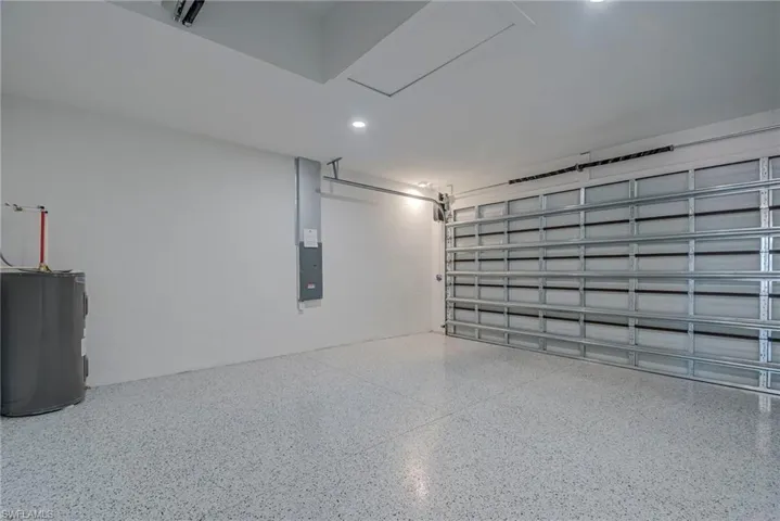 Garage featuring electric water heater, electric panel, and recessed lighting