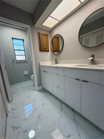 Full bathroom with double vanity and light marble finish floors