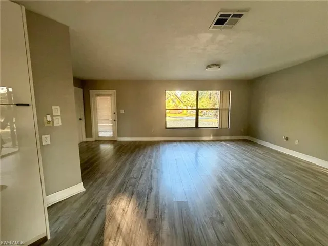 Unfurnished living room with dark wood-style floors and baseboards
