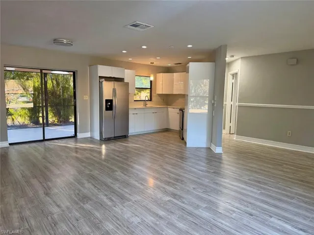 Unfurnished living room featuring dark wood-type flooring and recessed lighting