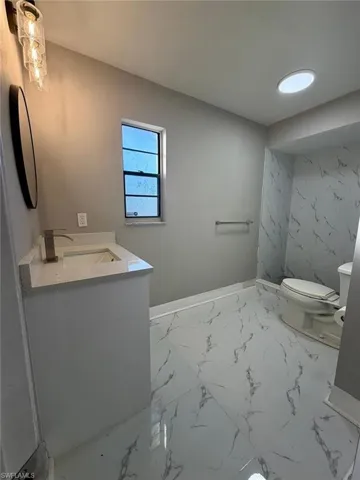 Full bath featuring vanity and light marble finish flooring