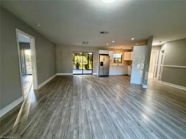 Unfurnished living room featuring dark wood-style floors and recessed lighting