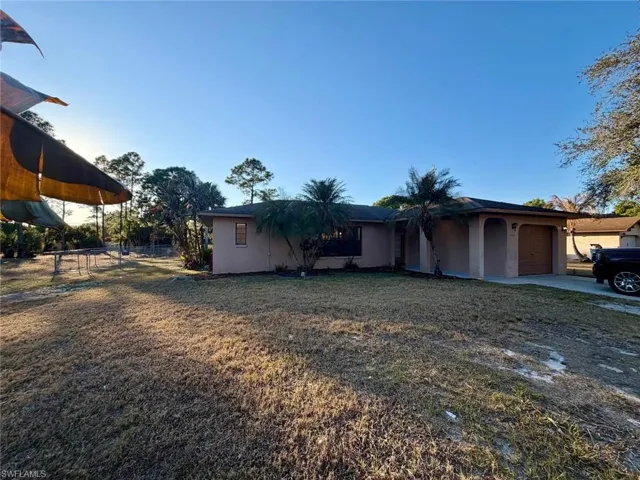 View of front of home featuring stucco siding, a garage, driveway, and a front lawn
