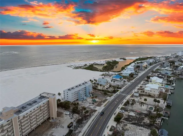 Aerial view at dusk featuring a water view and a beach view