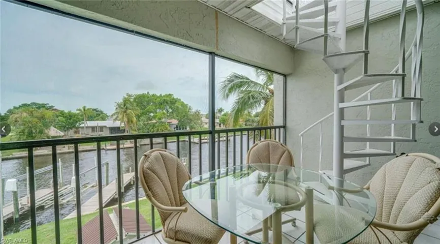Balcony with a sunroom, a water view, and outdoor dining area