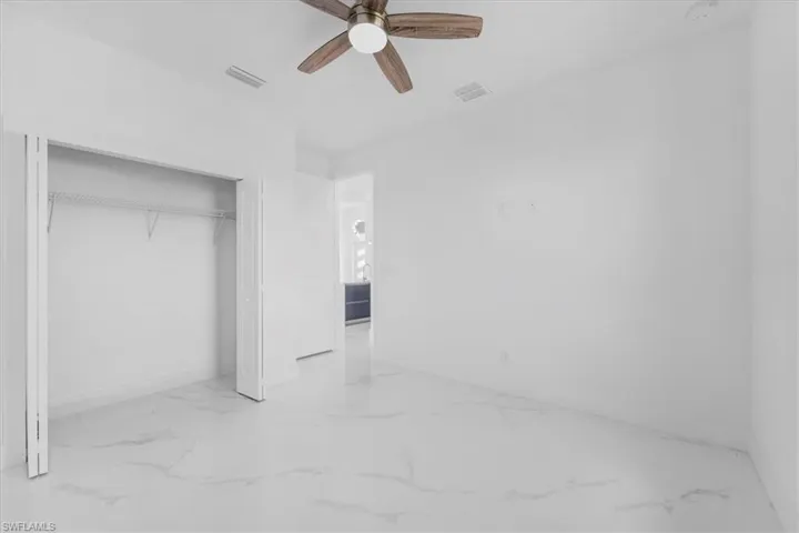 Unfurnished bedroom with ceiling fan, a closet, and light marble finish floors
