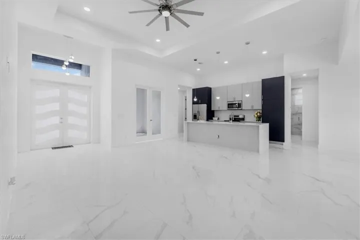 Unfurnished living room with a high ceiling, recessed lighting, a ceiling fan, and french doors