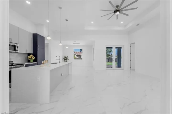 Kitchen featuring hanging light fixtures, stainless steel appliances, light stone counters, modern cabinets, and open floor plan