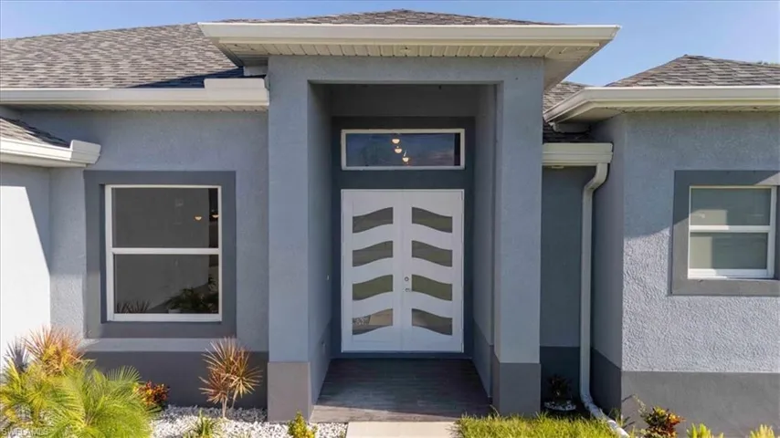 Property entrance featuring stucco siding, a shingled roof, and french doors