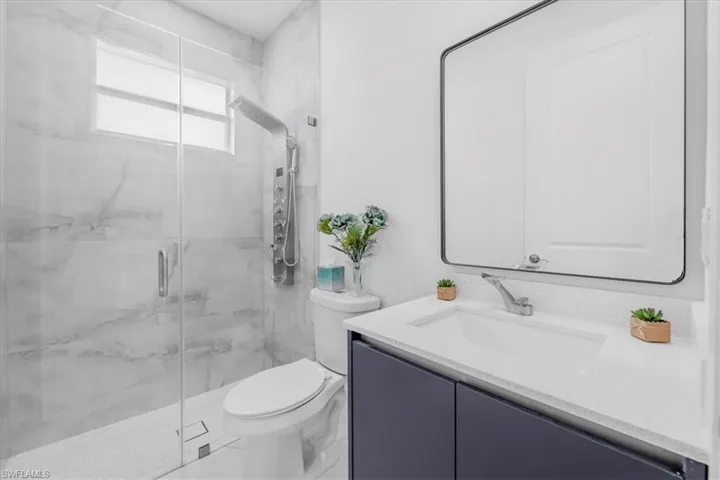 Bathroom featuring vanity and a marble finish shower