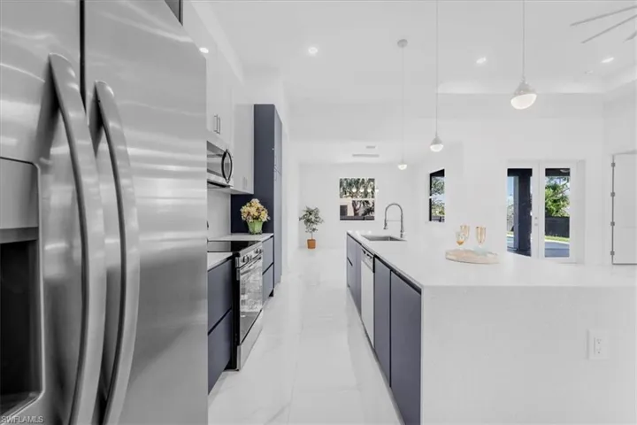 Kitchen with stainless steel appliances, modern cabinets, a spacious island, white cabinetry, and a raised ceiling