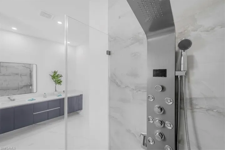Full bathroom featuring vanity, a marble finish shower, and recessed lighting