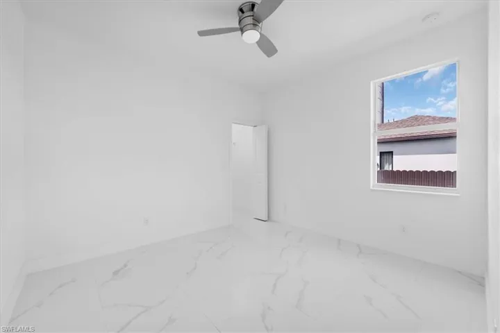 Empty room featuring ceiling fan and light marble finish flooring