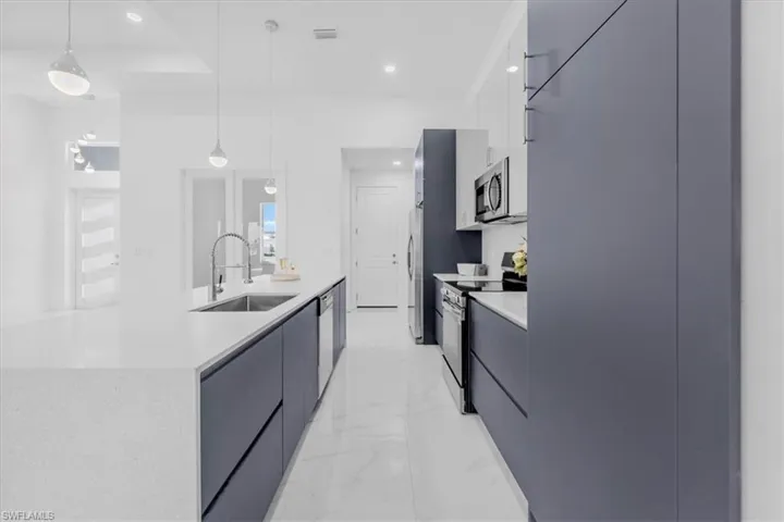 Kitchen with modern cabinets, stainless steel appliances, light stone countertops, and light marble finish floors