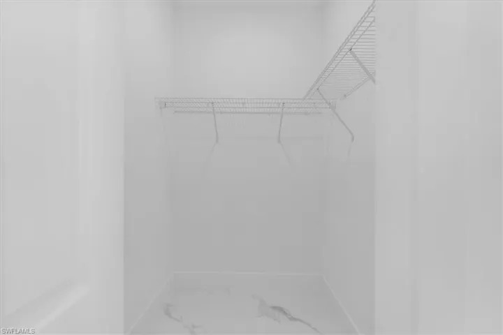 Walk in closet featuring light marble finish floors