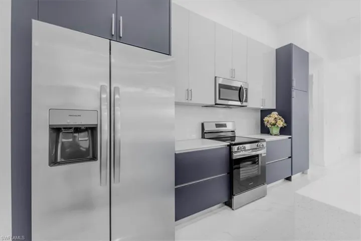 Dual tone kitchen featuring stainless steel appliances, modern cabinets, dual tone cabinetry, and light marble finish flooring