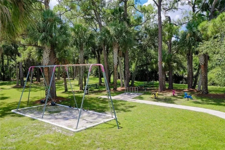 Outdoor recreational area featuring a paved walkway, mature canopy trees, and established landscaping