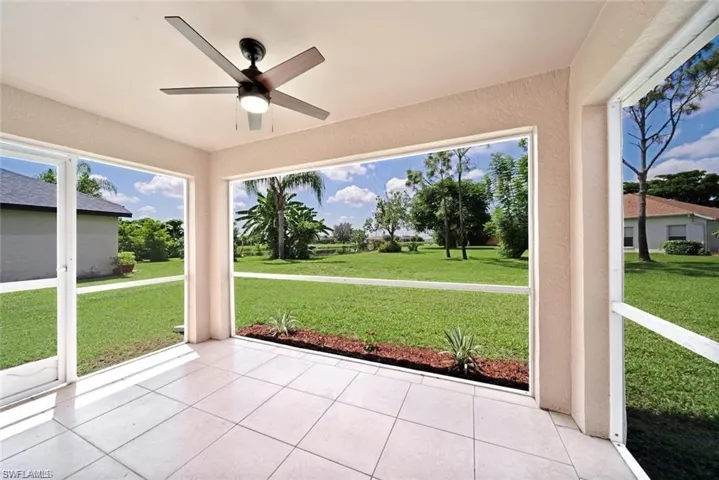 Screened-in lanai featuring large-format tile flooring, a ceiling fan with integrated lighting, and expansive window screening