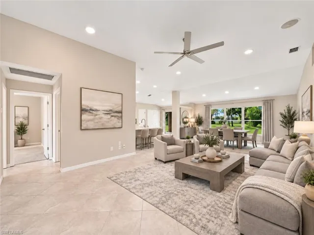 Open-concept interior featuring high vaulted ceilings, recessed lighting, neutral tile flooring, a ceiling fan, and large windows