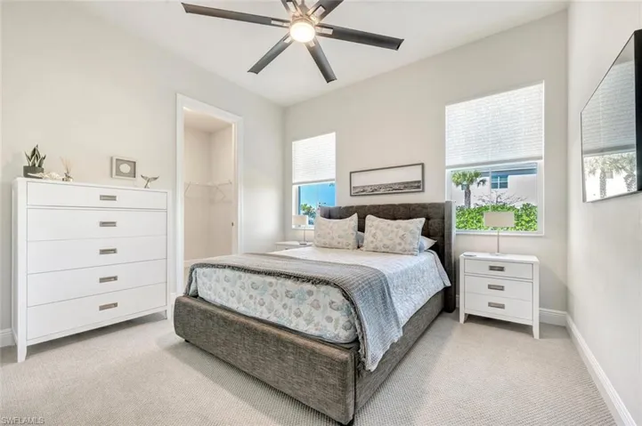 Bedroom featuring light colored carpet, a spacious closet, ceiling fan, and a closet