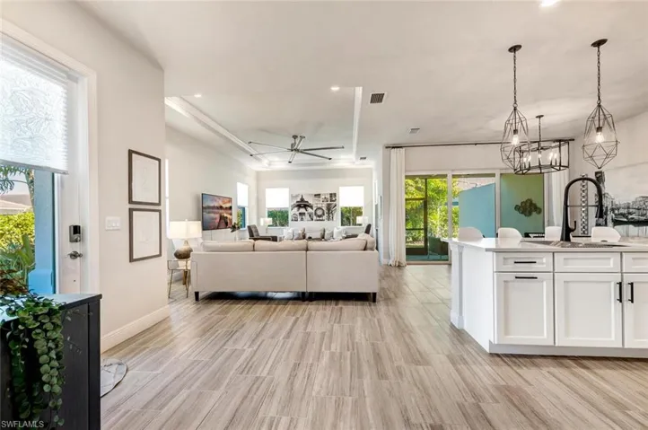 Living room with a tray ceiling and ceiling fan with notable chandelier