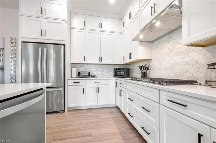 Kitchen featuring light hardwood / wood-style flooring, tasteful backsplash, white cabinetry, and appliances with stainless steel finishes
